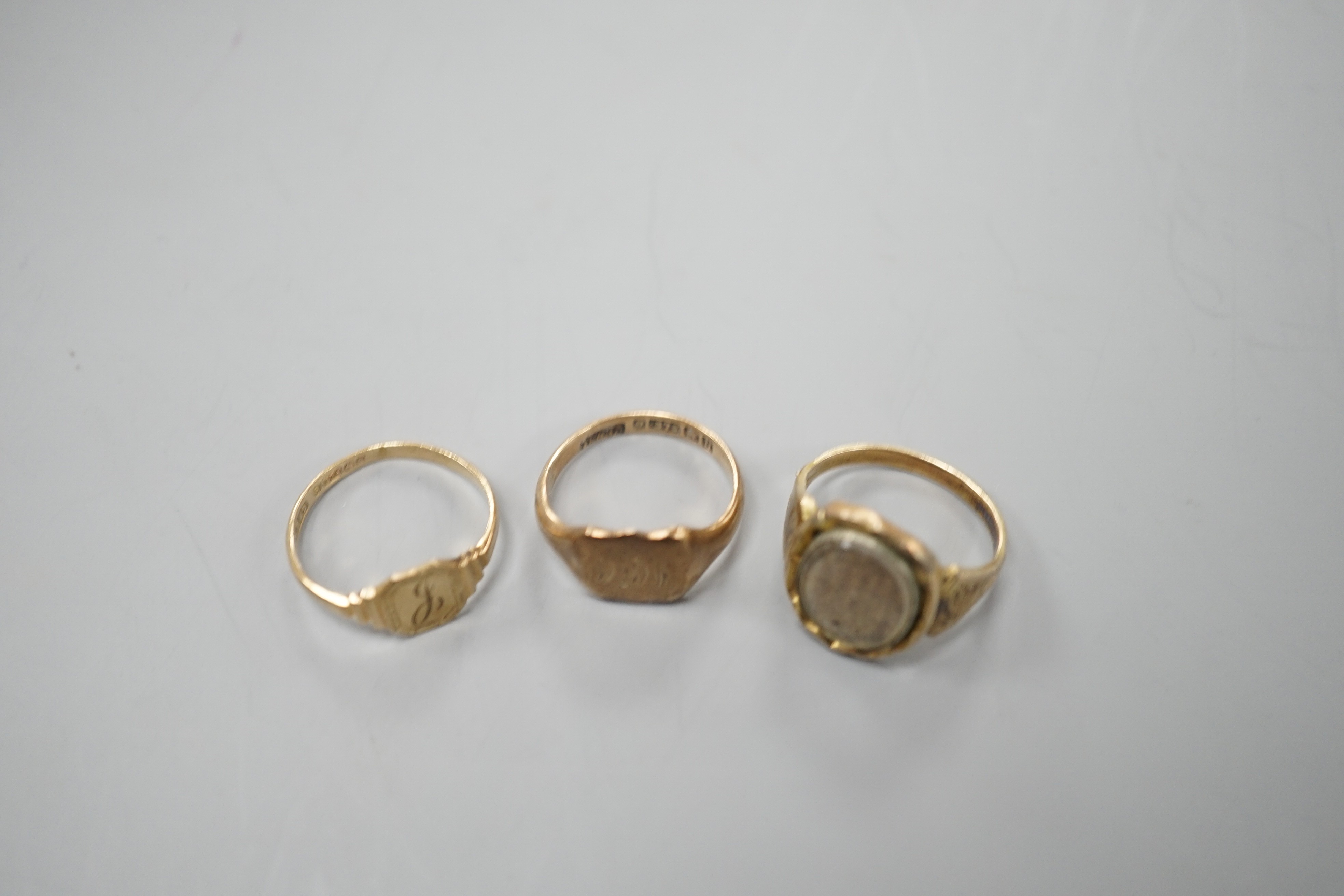 A 19th century yellow metal mourning ring, with plaited hair beneath a glazed panel size L, together with two later 9ct gold signet rings, gross weight 6.3 grams.